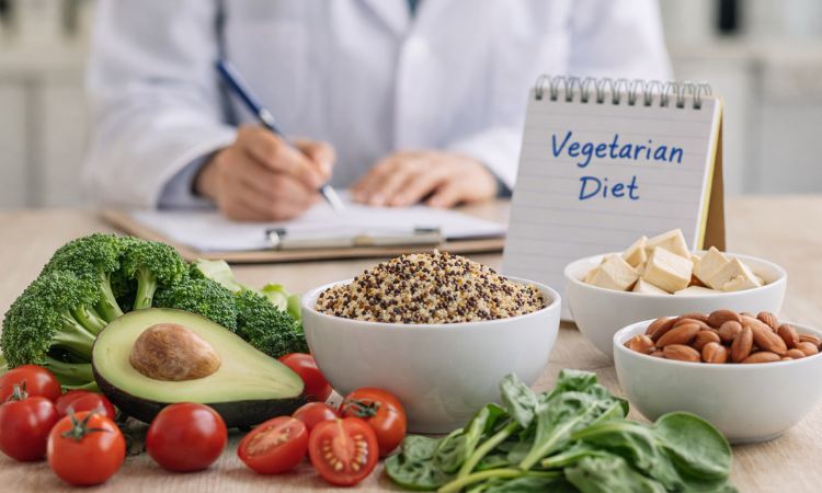 Alimentos vegetarianos frescos sobre una mesa, con un profesional de nutrición al fondo en un entorno de consulta.